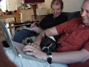 A field study facilitator watching a participant at home using a laptop to access a website, with a dog on the participant’s lap.