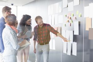 Young businessman explaining document to colleagues in creative office